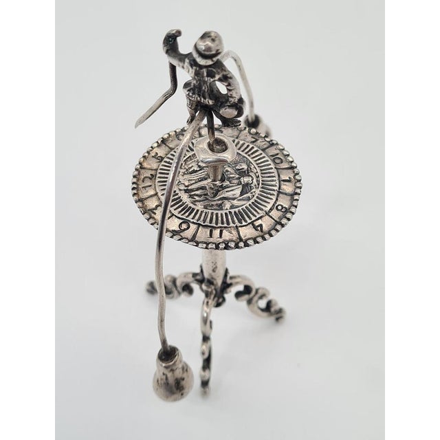 A unique, miniature functional sculpture made of silver, depicting a stylized figurative scene in the form of a historical...