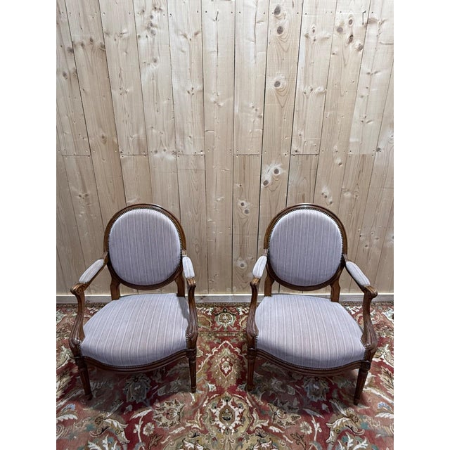 A pair of Louis XVI style cabriolet armchairs, testaments to classic and timeless craftsmanship. These two chairs, with...