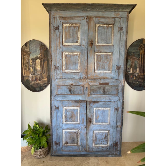 Spanish painted 19th c cabinet with distressed blue-painted finish, four doors, and two central drawer. With raised panel...