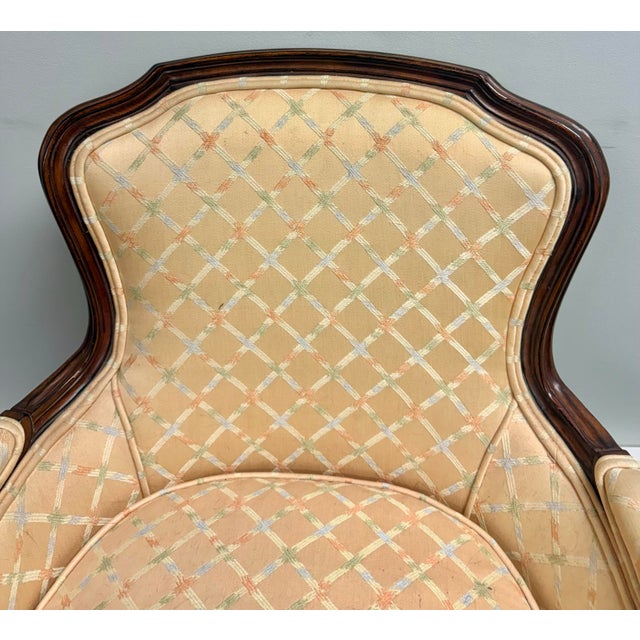 Beautiful vintage French-style bergère armchair featuring a graceful carved wood frame and classic curved silhouette....