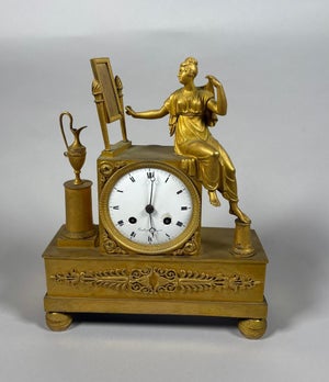 Empire period 19th century mantel clock depicting a woman at her toilette