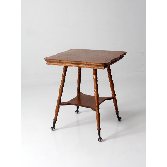 Early 20th century Edwardian oak side table with a shaped top, turned legs, and iron ball-and-claw feet with glass ball...