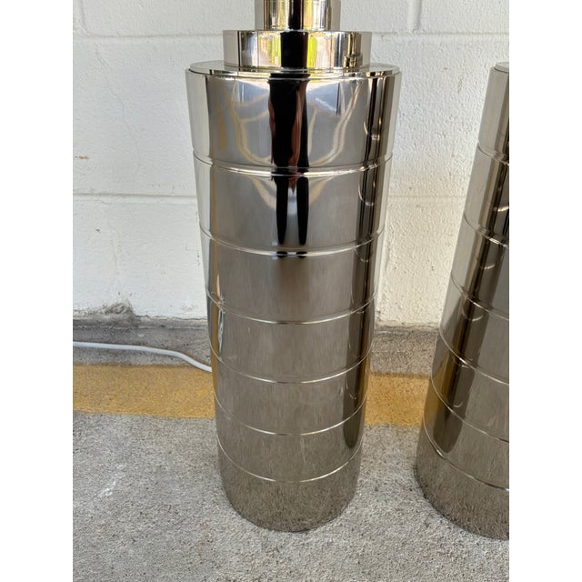 Stylish Ralph Lauren Modern Polished Nickel Lamps - Pair. Heavy body, silver hardware. Cylinder shape. Showroom floor sample.