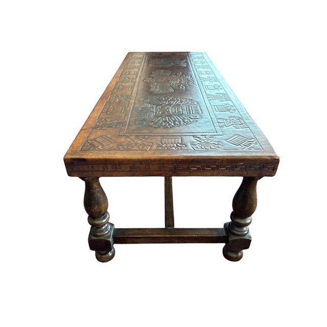 Decorative coffee table in Spanish Colonial Revival style, featuring a richly embossed leather top with stylized pre-...