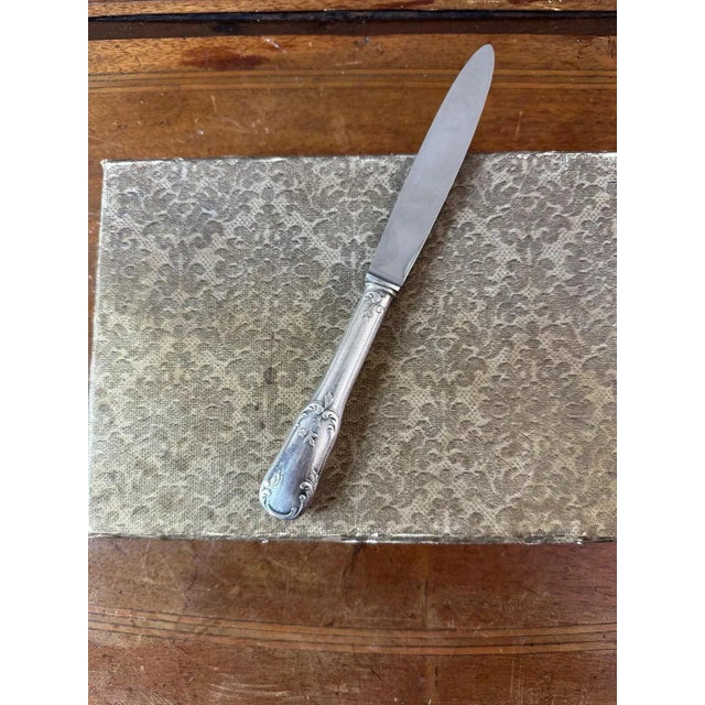 Box of 12 cheese knives in silver metal and stainless steel blade dating from the 1950s. Beautiful foliage decoration on...