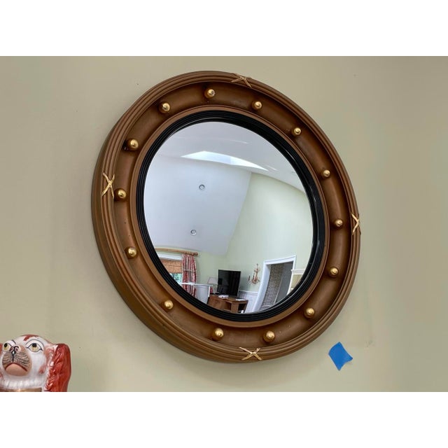 A Regency carved wood bullseye mirror with a circular carved-wood frame, round convex mirror, raised inner ring black trim...
