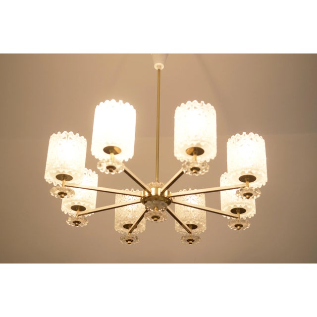This vintage chandelier was made in the 1970s in Austria. It features a brass construction with glass lamp shades. The...