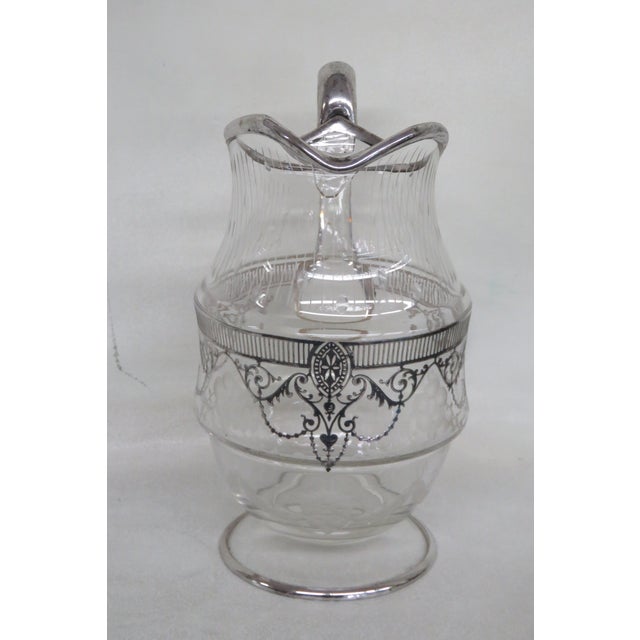 This gorgeous Pitcher is made of glass. This Pitcher features a fabulous etched flowers and silver overlay on the handle,...