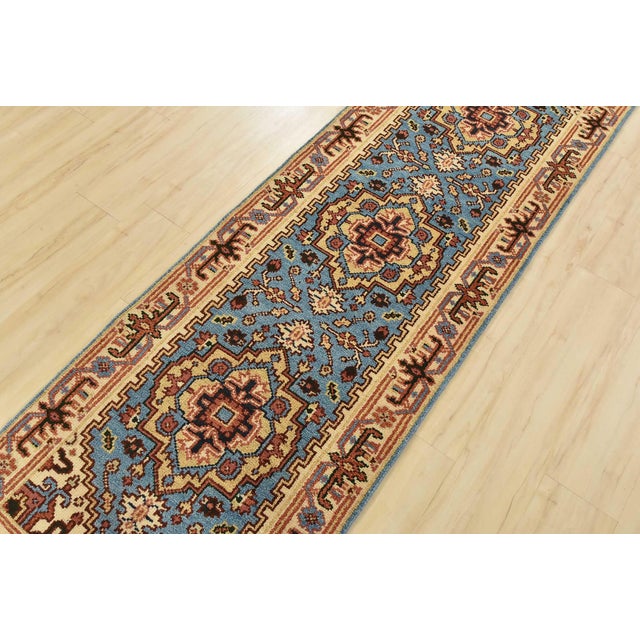 A traditional tribal Heriz runner hand-knotted with an all-wool pile on a cotton foundation. This oriental rug features...