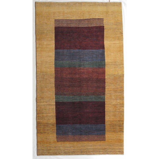 Vintage Hand-knotted Persian Lori Gabbeh rug featuring a warm golden-beige field with a vertically oriented central panel...