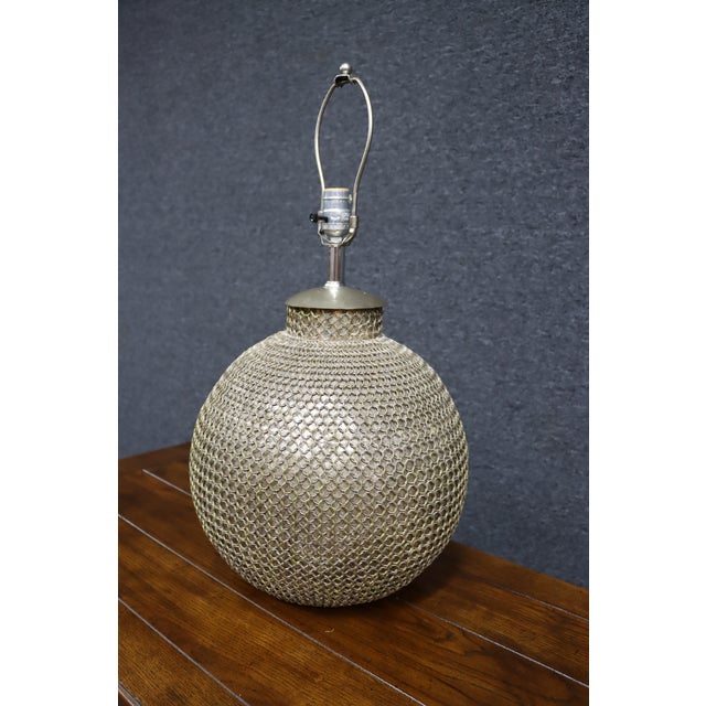 Mid-century modern table lamp featuring a spherical form wrapped in brass chainmail over an inner diffuser. The open metal...