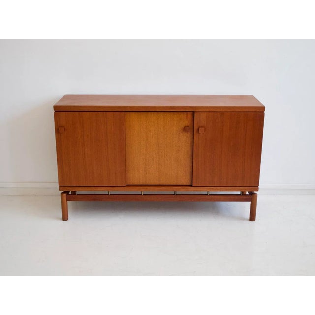 Sideboard made of teak wood with sliding doors and brass details. Manufactured and labeled by La Permanente Mobili Cantù....