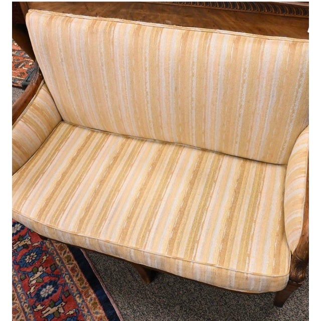 A handsome French Restoration period mahogany settee dating to the early 19th century, featuring a finely carved crest...