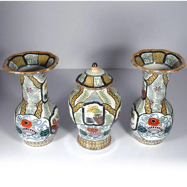 A large decorative set made of glazed Delft faience. Two vases and a vase with a cover decorated with a colorful...