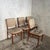 A matching set of four Nathan Furniture dining chairs with warm teak-toned frames and comfortably padded beige button-...