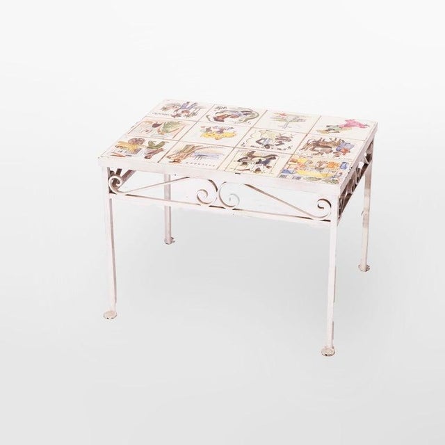An antique arts and crafts table offers a painted wrought iron frame having scroll form apron surrounding a top housing a...