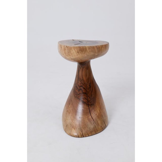 This elegant pedestal table is carved from a single piece of wood, showcasing fluid and organic lines that feel both...