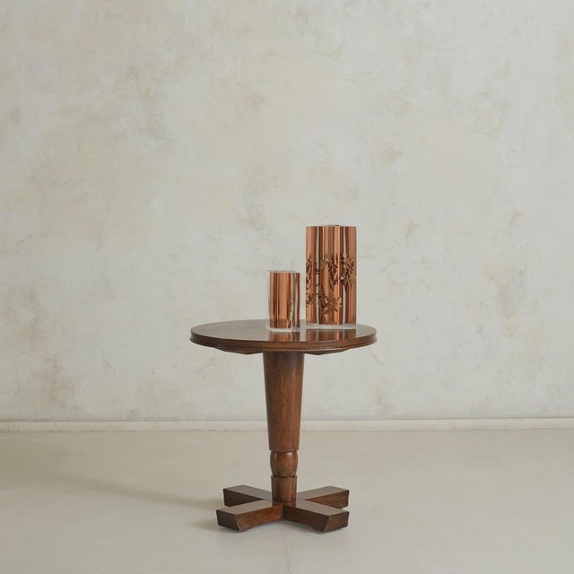 A French round pedestal accent table from the 1950s, crafted from solid wood. The circular top rests on a tapered central...