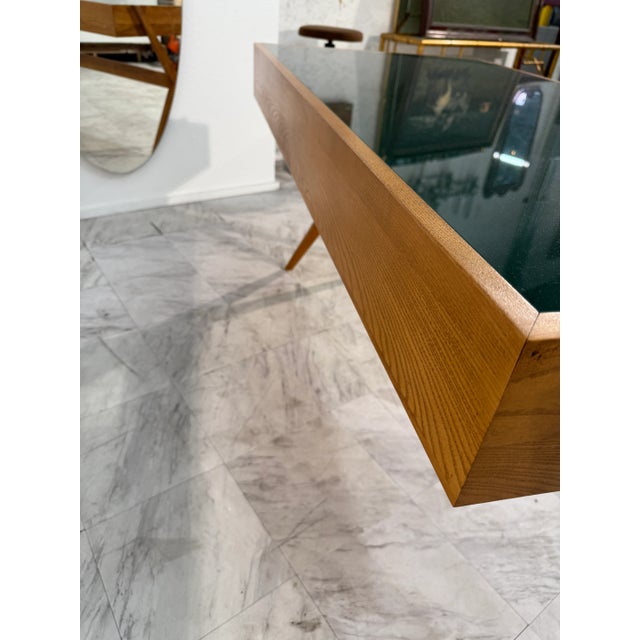 This is a modern Italian desk from around 1990s. It has a warm wood frame with angled legs and a dark green glass top. The...