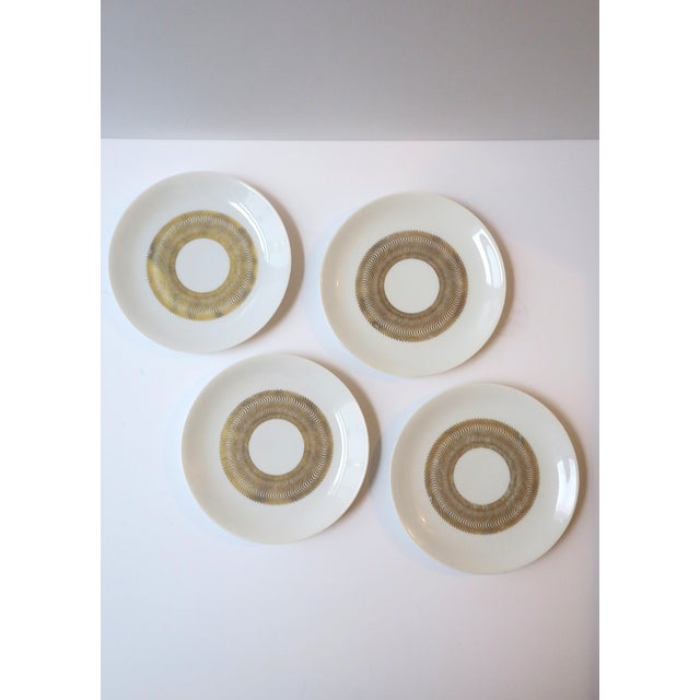 A set of four (4) white and gold small porcelain plates, French Modernism, designed by noted French Art Deco designer Jean...