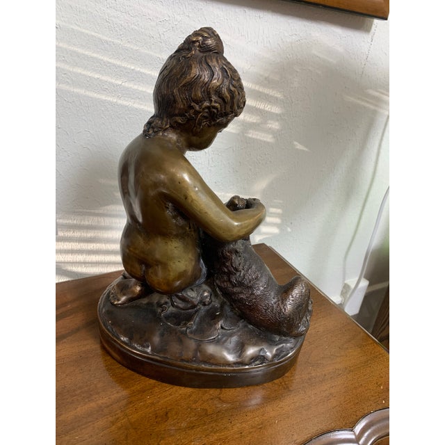 Charming vintage bronze-tone sculpture featuring a young child lovingly bathing or holding a dog on a naturalistic base....