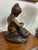 Charming vintage bronze-tone sculpture featuring a young child lovingly bathing or holding a dog on a naturalistic base....