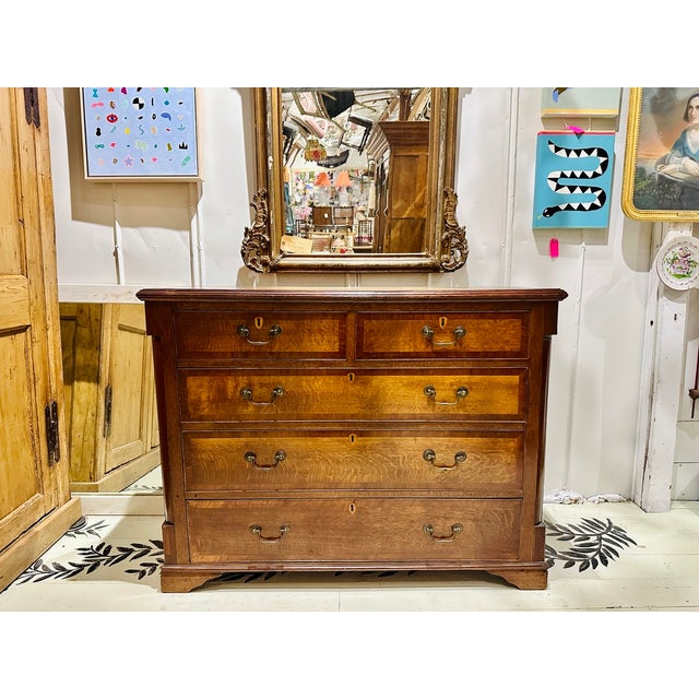 A beautifully crafted English Georgian chest featuring richly figured tiger oak drawer fronts framed by contrasting...