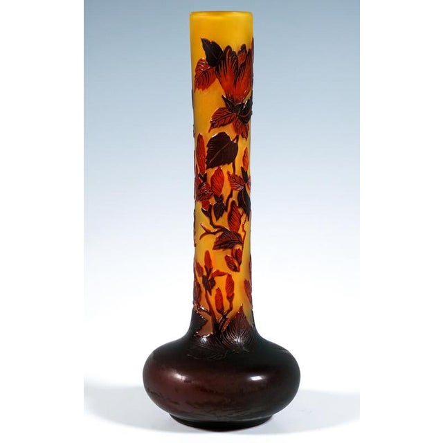Tall vase with a disc-shaped base on a ring stand and a long, slender, straight neck; colourless glass with yellow-orange...