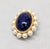 Goldtone cabochon faux-lapis with gold specks throughout and faux-pearl brooch with security clasp. Marked "Napier."...