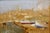 An atmospheric and evocative harbor scene depicting beached fishing boats on the shore with a hilltop village rising...