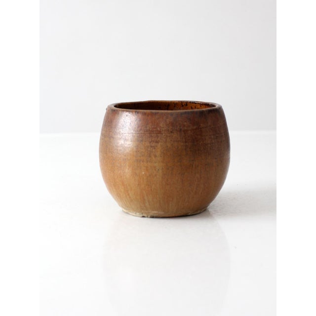 This vintage handmade studio pottery bowl features a rounded form and a warm glaze that transitions from rich brown to...