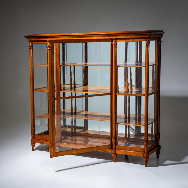 Large Biedermeier display cabinet in cherrywood with glazing on three sides and a mirrored back. The cabinet features a...