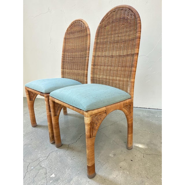 Pair of vintage wicker dining chairs with tall arched backs and finely wrapped frames. Elegant proportions with sculptural...