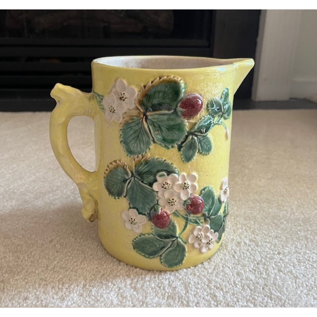 7 1/2" tall majolica water pitcher with strawberry plant details on both sides and orange peel textured finish. It is pale...