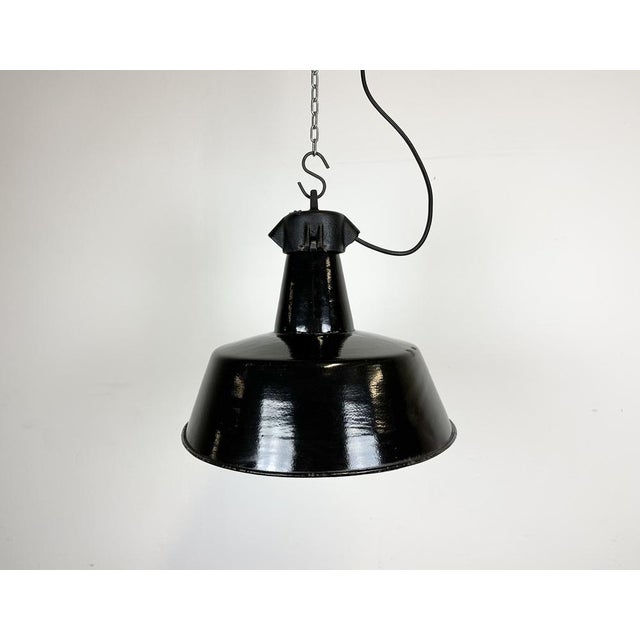 Industrial black enamel pendant light made in former Czechoslovakia during the 1960s. White enamel inside the shade. Cast...