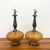 A striking pair of vintage table lamps featuring oversized amber crackle glass bodies complemented by ornate cast metal...