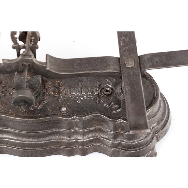 An antique French iron and brass balance scale with a decorative iron base bearing the name Breveté S.D.D.G. with raised...