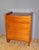 A designer chest of drawers circa 1970 in cherry wood, featuring four drawers, gilt bronze mounts, and a varnished finish;...