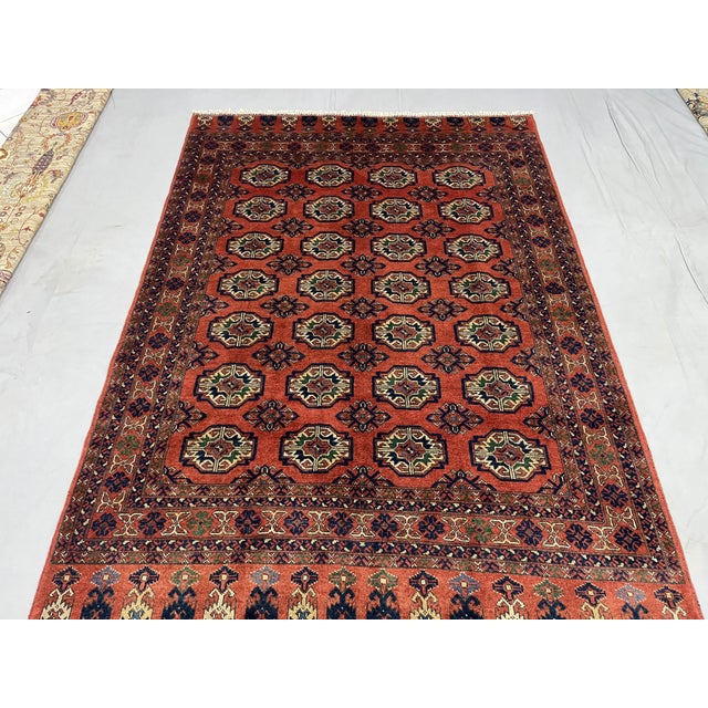 Bring warm color and rhythmic pattern to your home with this red wool area rug featuring a Turkmen Philpa tribal design....
