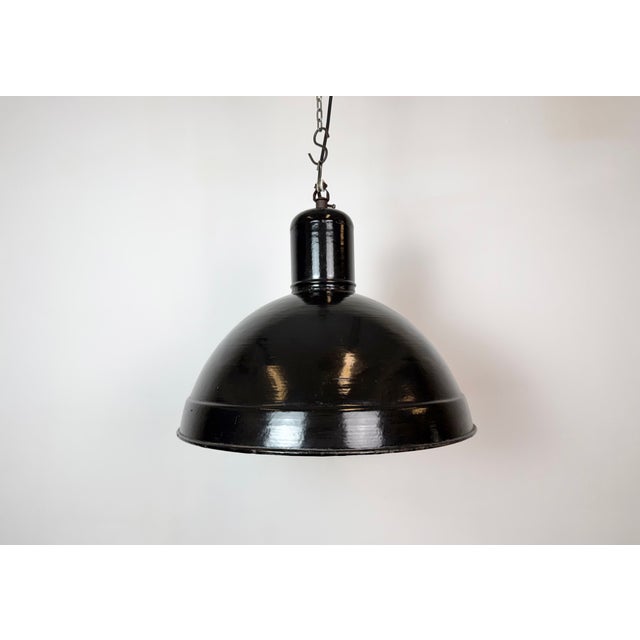 Industrial factory hanging lamp made in former Czechoslovakia during the 1950s. It features a black enamel shade with...