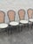 Set of four vintage dining chairs featuring black wrought iron frames with curved backs, natural cane insets, and round...