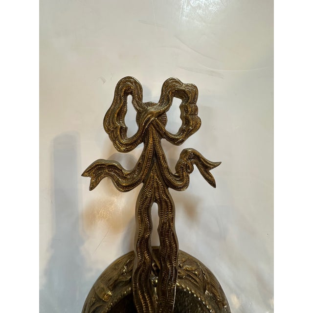 Elegant pair of vintage brass French style wall sconces each having two arms with candle lights, pretty bows on top and...