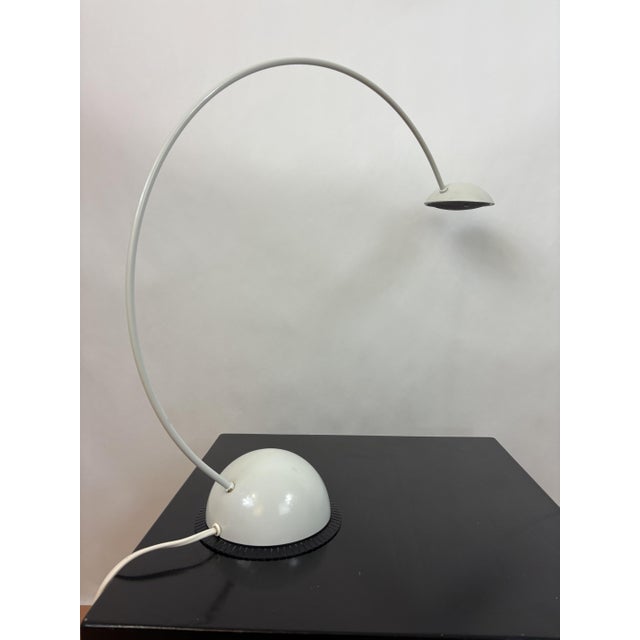 Elegant white metal table lamp from the 1980s with a round, spherical base resting on a black plastic flat base and arched...