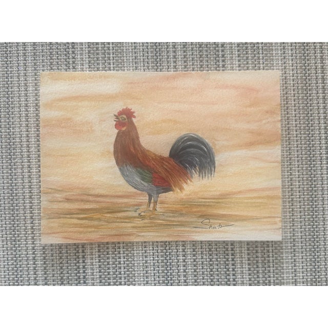 This charming rooster stands proudly against a warm sunrise backdrop. Rich earth tones and soft washes create a rustic...