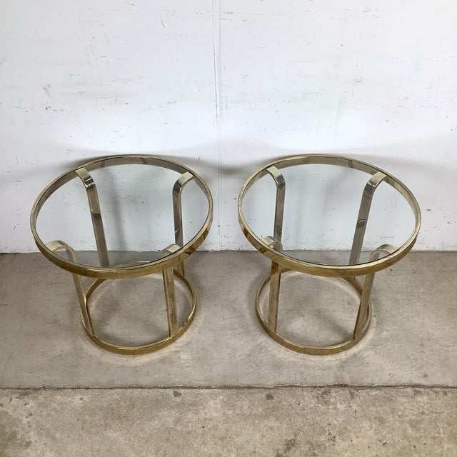 This matching pair of vintage brass and glass side tables features a streamlined design defined by clean lines and...