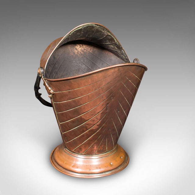 This is an antique coal scuttle. An English, copper and wrought iron fireside fuel basket in Art Nouveau taste, dating to...