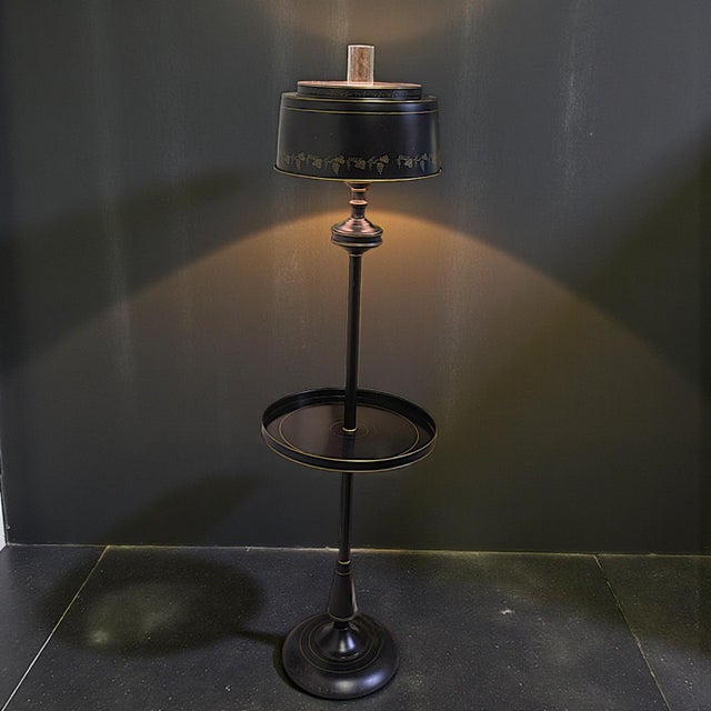 Mid-century black tabled floor lamp has a galleried tole shade with gold toned highlights. It is 1980s quality fine...
