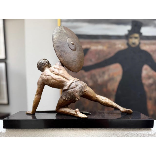 A striking and highly expressive figural sculpture depicting a reclining warrior in a moment of tension and movement,...