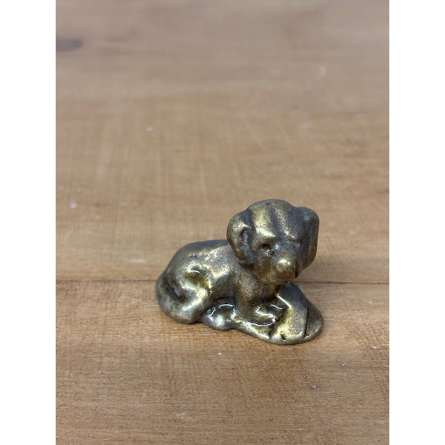 This sweet little vintage English brass dog figurine captures a tender moment, resting in a calm, laying-down pose. With...