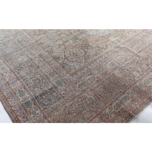 An antique Persian Kirman handmade wool rug dating back to 1930. The main field carries trellis of lozenge design filled...